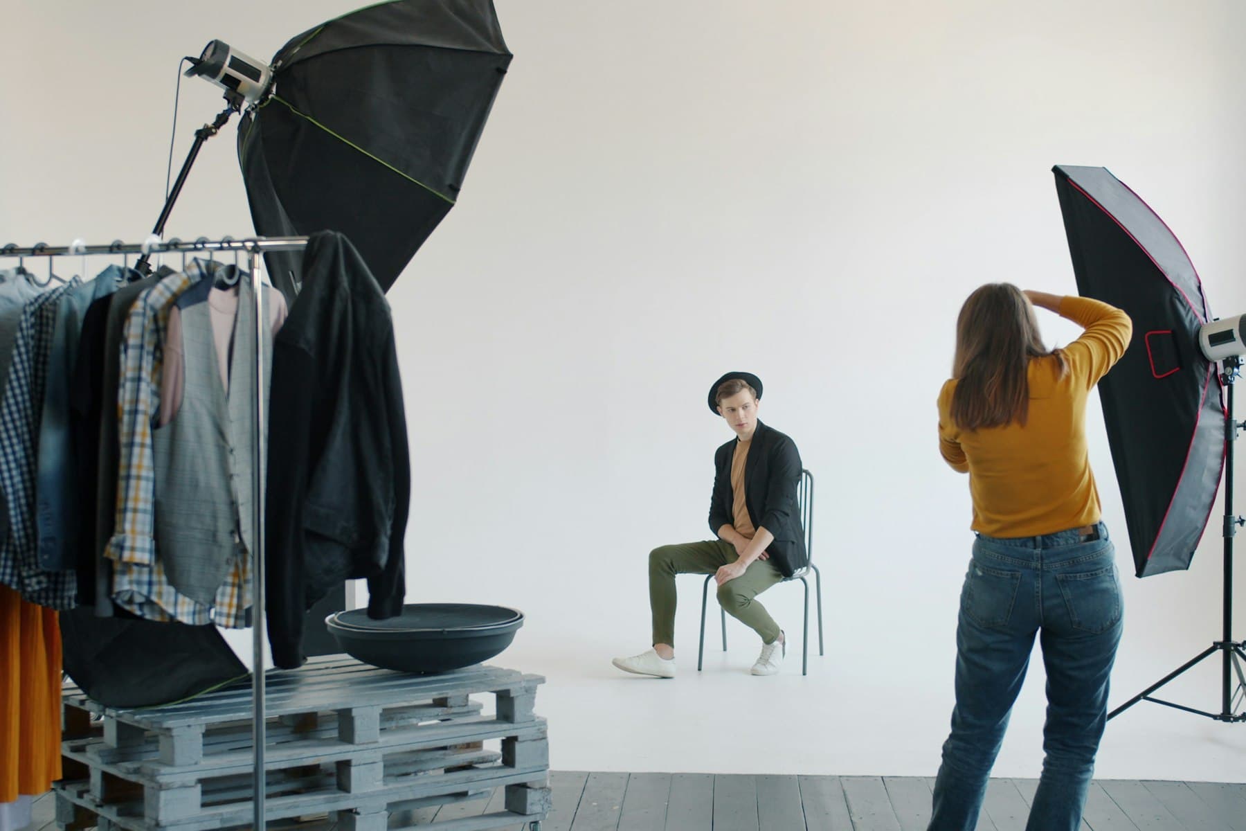 Studio portrait session in progress — photographer working with a subject between softboxes