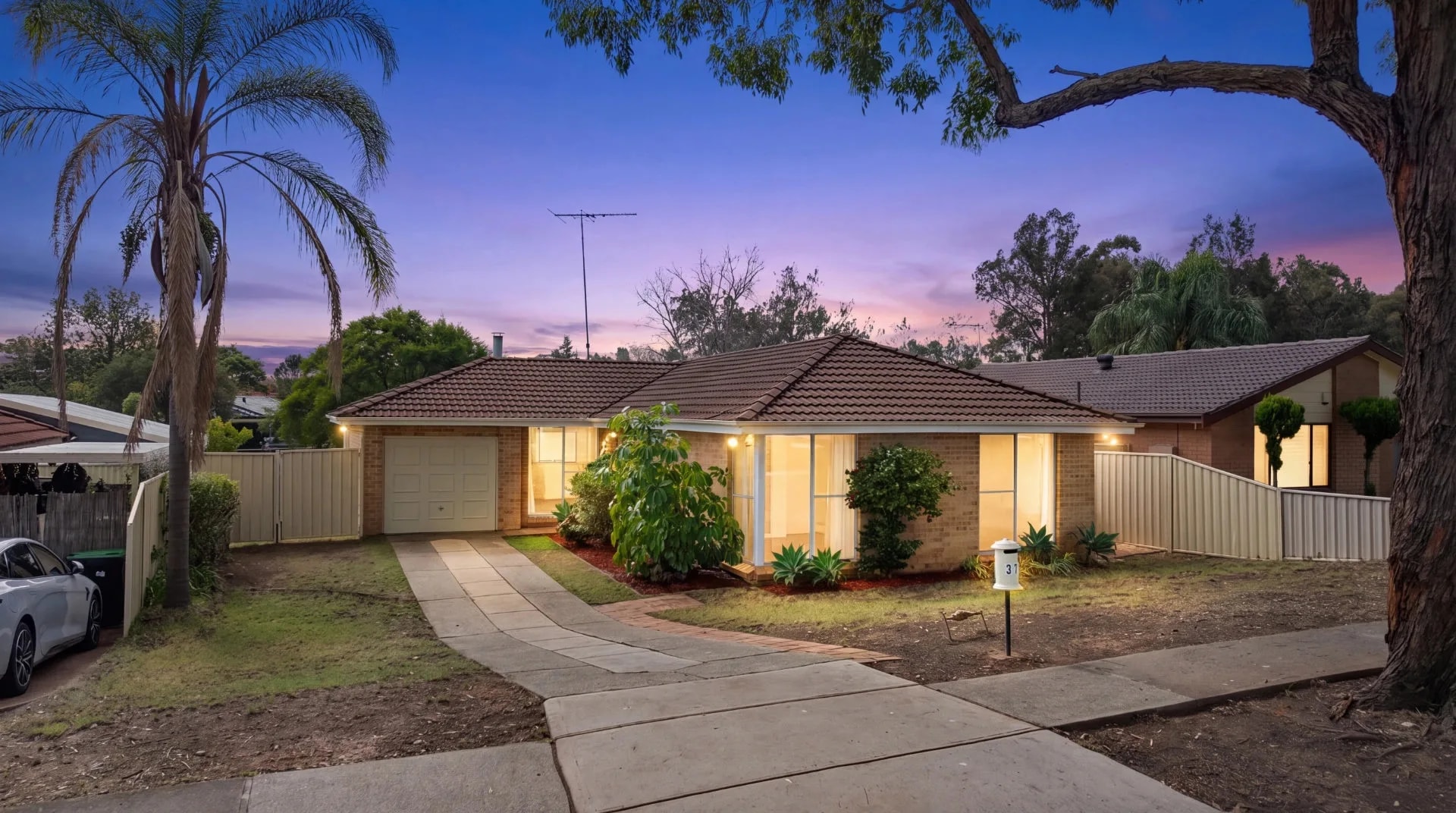 The same Sydney home captured at dusk, windows glowing under a violet sky